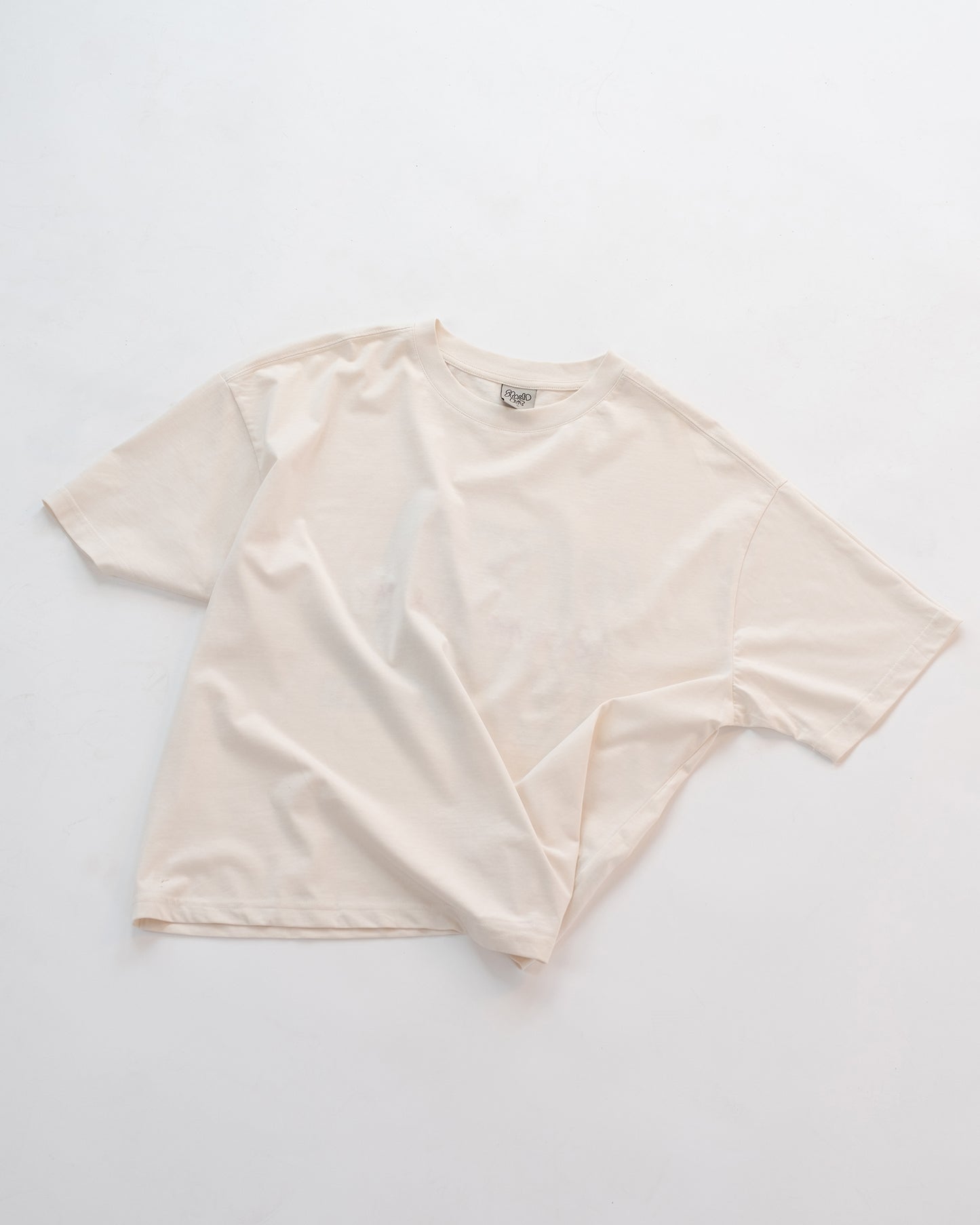 Schlichtes weißes Oversized-T-Shirt ohne Aufdruck, flach auf weißem Hintergrund liegend. Minimalistisches Basic-Shirt aus weicher Baumwolle – ideal kombinierbar für Unisex-Streetwear-Looks.