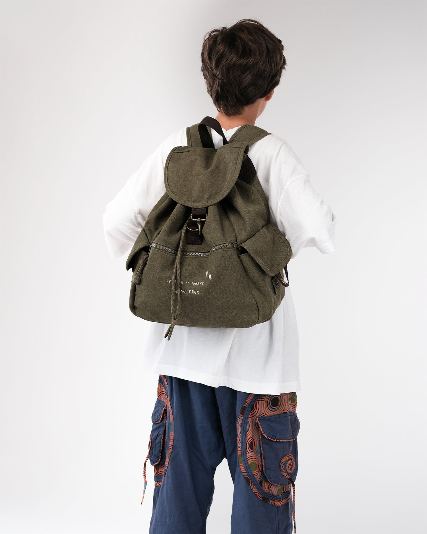 Olivgrüner Canvas-Rucksack am Rücken, zeigt Volumen und Form; gepolsterte Träger, Front-Reißverschlussfach mit Stickerei, seitliche Pattentaschen.