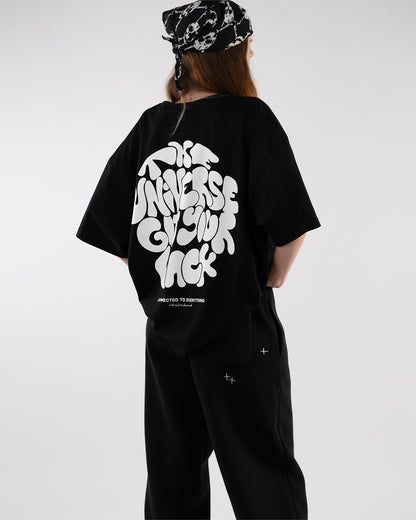 Frau mit schwarzem Bandana trägt ein schwarzes T-Shirt mit großem weißen Schriftzug auf dem Rücken: „The Universe Got Your Back“