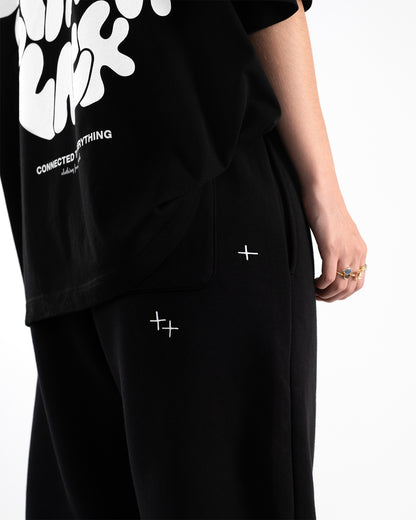 Nahaufnahme vom oberen Gesäßbereich der Jogginghose: zwei kleine, gekreuzte Sticksterne über der Gesäßtasche. Die Hose wird kombiniert mit einem schwarzen T-Shirt.