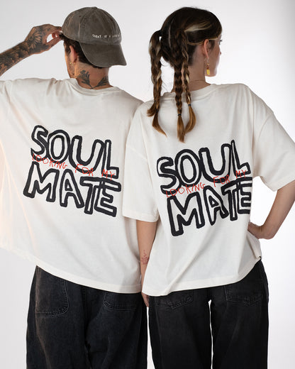 Zwei Personen stehen Rücken an Rücken und tragen weiße Oversized-T-Shirts mit schwarzem und rotem Rückendruck „Looking for my Soul Mate“. Beide Outfits sind im lässigen Unisex-Streetwear-Stil mit dunklen Jeans gestaltet – modernes Partner-Look-Shirt mit verspielter Botschaft.