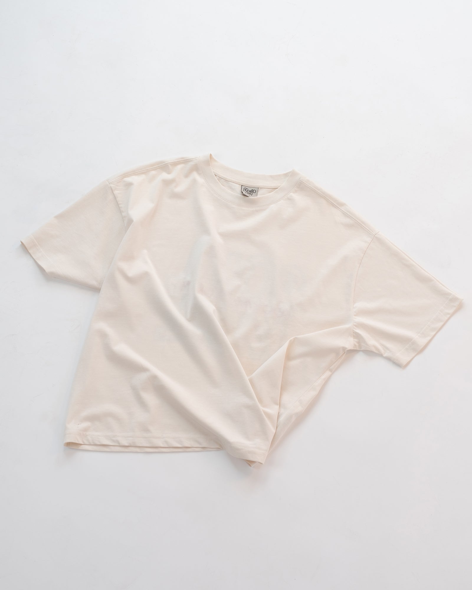 Schlichtes weißes Oversized-T-Shirt ohne Aufdruck, flach auf weißem Hintergrund liegend. Minimalistisches Basic-Shirt aus weicher Baumwolle – ideal kombinierbar für Unisex-Streetwear-Looks.
