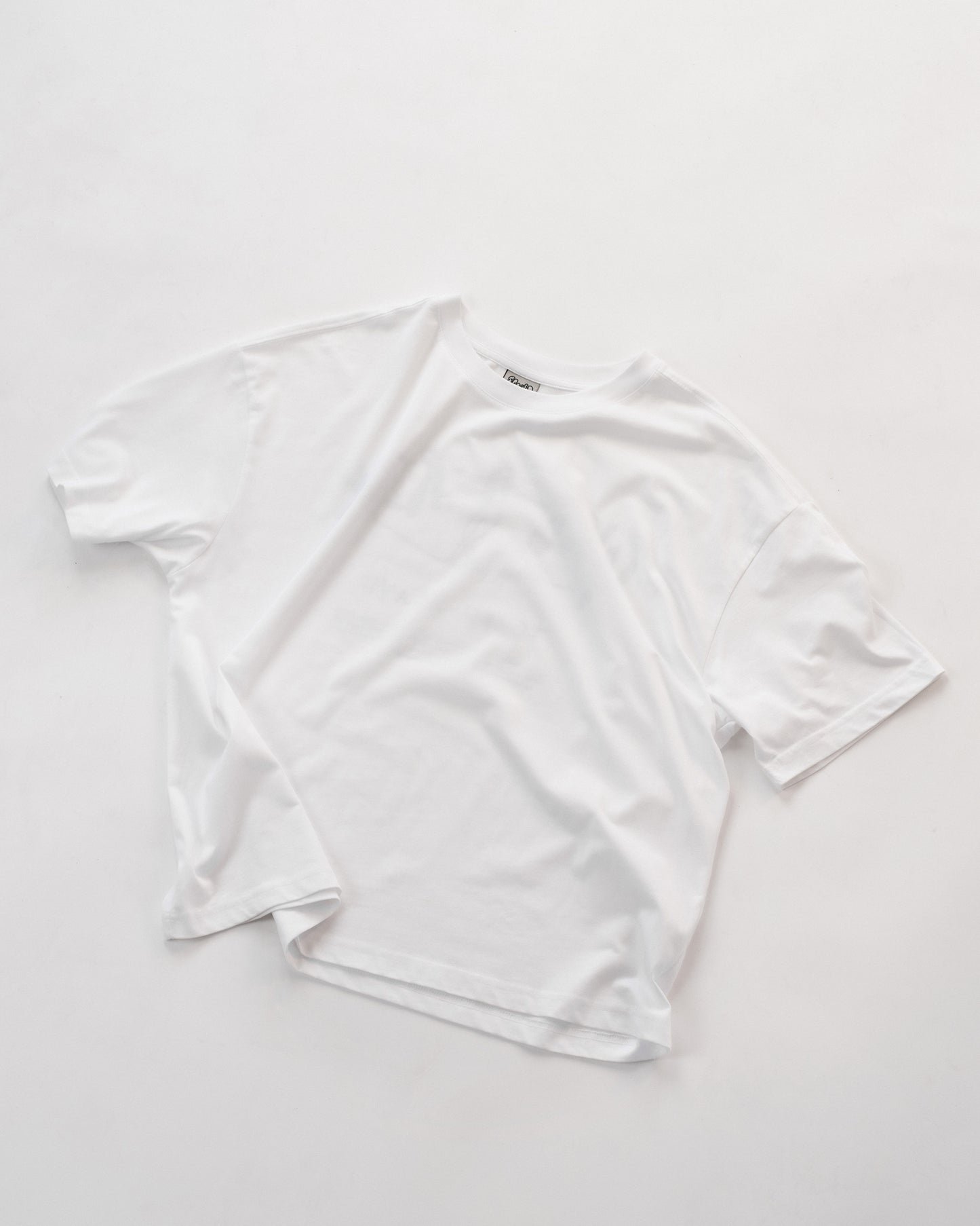 Schlichtes weißes Oversized-T-Shirt, Vorderseite sichtbar, ohne Aufdruck. Das Shirt liegt flach auf weißem Hintergrund – minimalistisches Basic-Design aus weicher Baumwolle, perfekt für vielseitige Unisex-Streetwear-Looks.