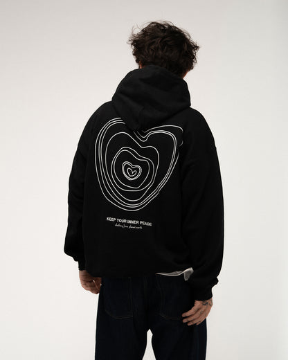 Schwarzer Kapuzenpullover mit großem weißen Liniengrafikdruck auf dem Rücken, der konzentrische Herzen darstellt, darunter der Text „KEEP YOUR INNER PEACE – clothing from planet earth“.