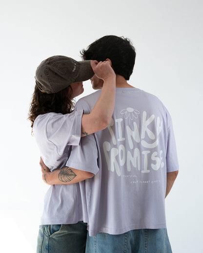 Zwei Personen umarmen sich in fliederfarbenen Oversize-T-Shirts; Rückenprint deutlich sichtbar: „PINKY PROMISE“ mit Blüte darüber.
