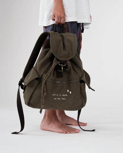 Olivgrüner Canvas-Rucksack (Seitenansicht); Kordelzug und Überschlag mit Metallhaken, Front-Reißverschlussfach mit Stickerei, seitliche Pattentaschen, lange Kordelenden.