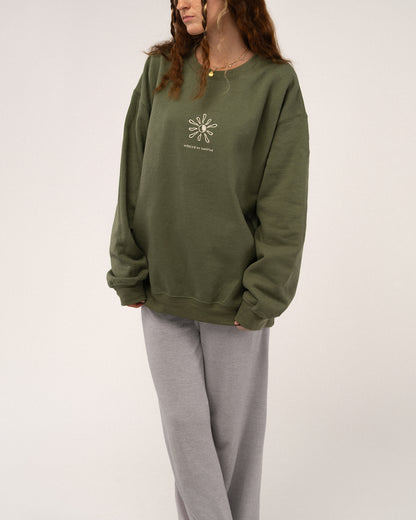 Grünes Sweatshirt mit beiger Stickerei „walking on sunshine“, kombiniert mit grauer Jogginghose für einen lässigen Look.