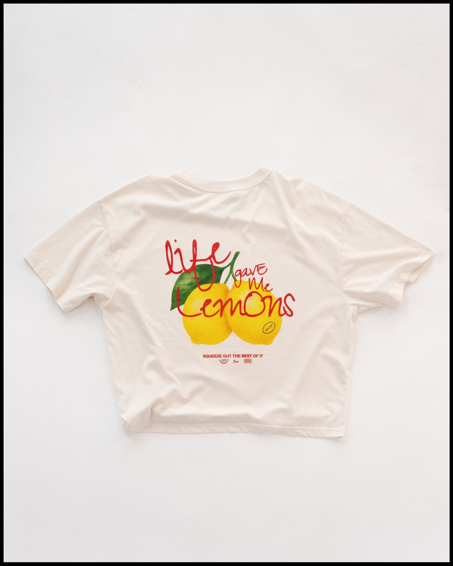 Weißes T-Shirt mit farbenfrohem Aufdruck auf der Rückseite: Zwei gelbe Zitronen mit grünen Blättern und roter Schrift „Life gave me lemons – squeeze out the best of it“. Locker geschnitten, lässiger Sommer-Look.